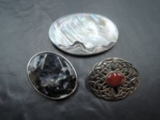 Three silver brooches including Celtic knot, stylised shell and moss agate