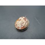 A conch shell cameo brooch/pendant of circular form depicting an angel with cherub and garland in