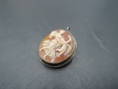 A conch shell cameo brooch/pendant of circular form depicting an angel with cherub and garland in