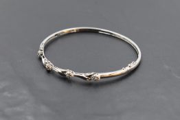 A white metal hinged bangle stamped 9K having moulded foliate & floral decoration, approx 10g