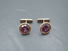 A pair of yellow metal cufflinks stamped 14A having facet cut heat treated amethyst stones and bar