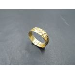 An 18ct gold wedding band having engraved floral and foliate decoration, size T/U & approx 3.1g