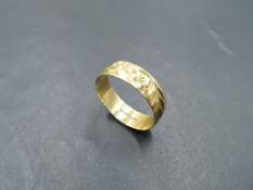 An 18ct gold wedding band having engraved floral and foliate decoration, size T/U & approx 3.1g