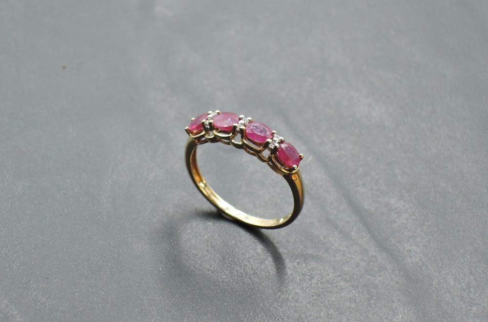 A 9ct gold dress ring having four oval ruby style stones with diamond chip spacers on a 9ct gold