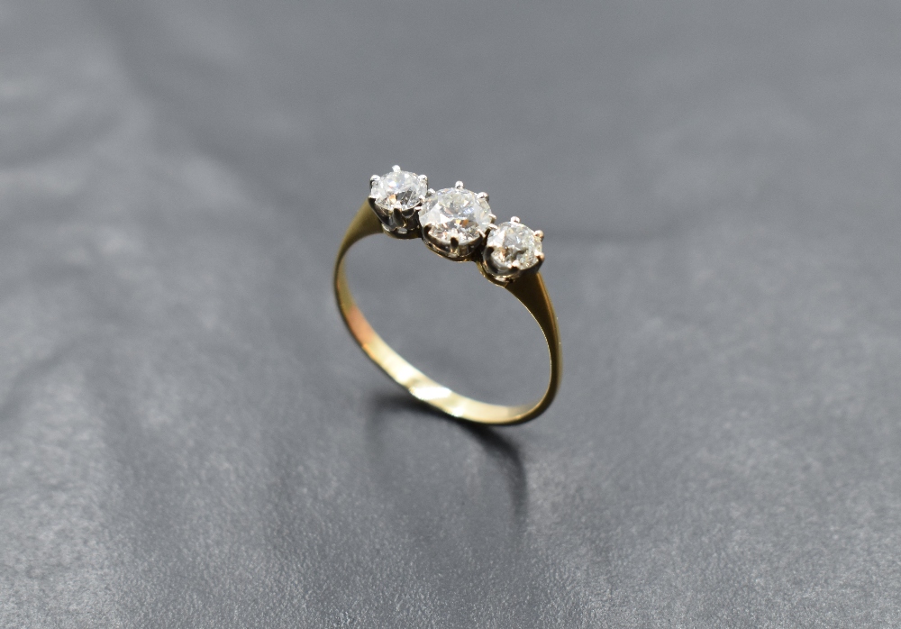 A diamond trilogy ring, total approx 1.25ct in a claw set mount on a yellow metal loop, no marks,