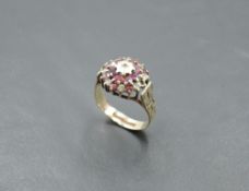 A ruby and diamond chip triple cluster ring in a claw set basket mount with engraved shoulders on