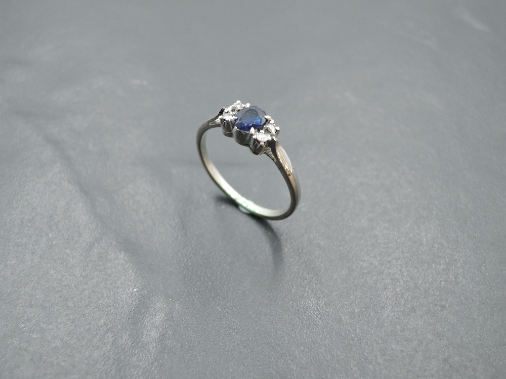 A sapphire dress ring flanked by diamond chips with knife blade shoulders on a white metal loop, - Image 2 of 4