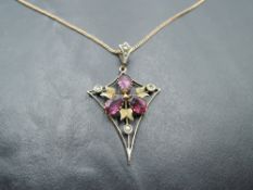 An Edwardian style yellow metal pendant of kite form having red paste and seed pearl decoration on a