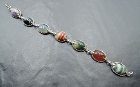 A seven panel mixed agate bracelet in white metal collared mounts stamped silver with chain