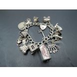 A white metal charm bracelet having sixteen HM silver and white metal charms including opening