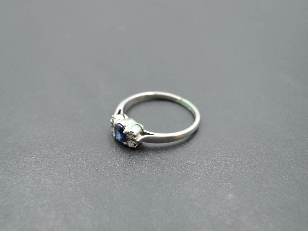 A sapphire dress ring flanked by diamond chips with knife blade shoulders on a white metal loop, - Image 3 of 4