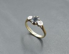 An oval sapphire ring flanked by two diamond chips in illusionary mounts on a 9ct gold loop, size