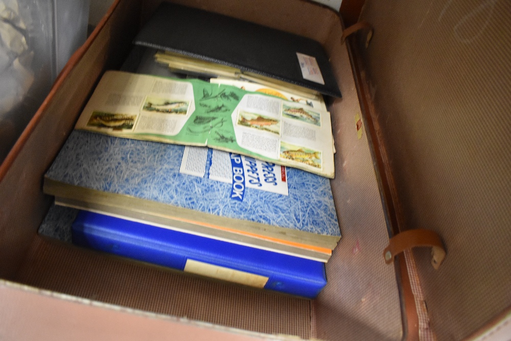 A suitcase containing an assortment of Brooke bond albums, various interests to include flowers,