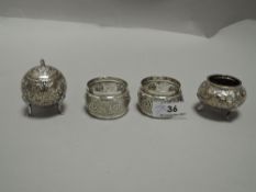 A pair of Eastern white metal condiments, with moulded foliate scroll decoration and three