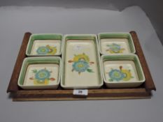 An Art Deco Clarice Cliff Wilkinson set of five hand decorated dishes with oak tray.