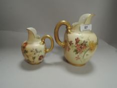 Two Royal Worcester blush ivory jugs having gilt handles with hand painted floral scenes larger