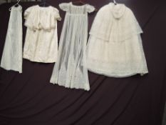 A collection of early 20th century baby clothes to include quilted cape with lace overlay, a silk