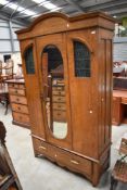 A late Victorian/ Edwardian oak wardrobe having textured green glass and leaded windows two front,