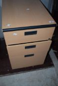 A laminate office chest of two shallow and one deep filing drawer