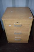 A laminate oak effect three drawer office or bedside chest