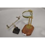 A vintage style brass magnifying glass with wood base and a clamp.