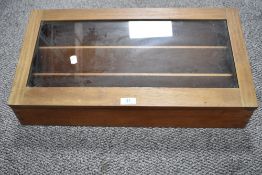 A mahogany table top display case having three horizontal internal compartments and glass lid.
