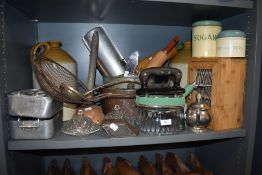 A shelf full of vintage and antique kitchenalia, including enamel storage tins, stoneware flagon,