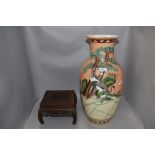 A large oriental styled lamp base, having orange ground with storks amongst shrubbery, chip to