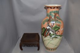 A large oriental styled lamp base, having orange ground with storks amongst shrubbery, chip to