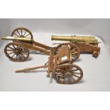 Two brass and wood model canons and a cart.