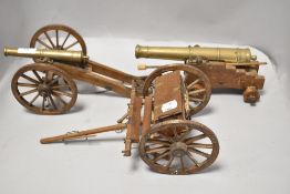 Two brass and wood model canons and a cart.