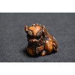 An early 20th century Japanese carved wood Netsuke of a Chinese mythical Pixiu with ball