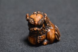 An early 20th century Japanese carved wood Netsuke of a Chinese mythical Pixiu with ball
