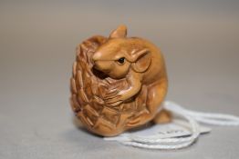 An early 20th century Japanese Netsuke carved as a mouse holding onto a Conifer cone