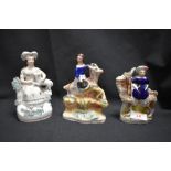 Three Staffordshire flatback figures including ladies sat on goats and a lady with dog on lap