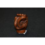 An early 20th century Japanese carved wood Netsuke of a human hand holding a Snake