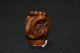An early 20th century Japanese carved wood Netsuke of a human hand holding a Snake