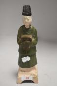 An antique Chinese figure of a servant holding a box in a Ming dynasty style with polychrome body