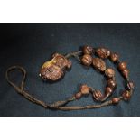 A 20th century Japanese necklace in carved wood with a figure of Geisha girl and hand carved beads