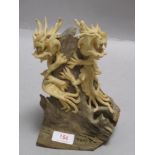 A modern Chinese double dragon figure in ceramic perched on a natural log