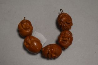 A set of five early 20th century Japanese Ojime carved wood beads of changing heads