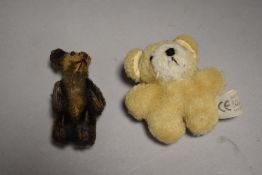 An early 20th century miniature teddy bear with jointed limbs and similar modern bear