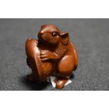 An early 20th century Japanese carved wood Netsuke of a Rat holding a small Carp fish