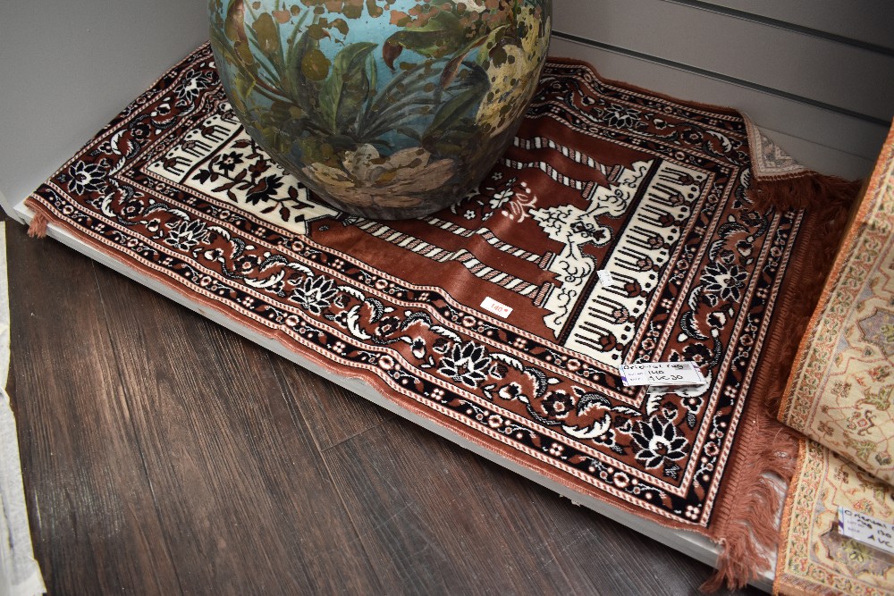 An Oriental fringed rug or prayer mat.