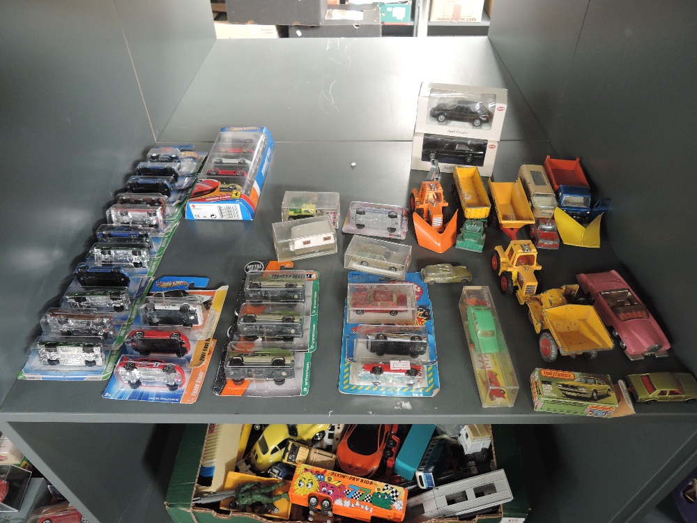 A shelf of mixed diecasts including modern Mattel Hot Wheels in blister packs, similar Matchbox,