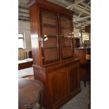 A Victorian mahogany bookcase over cupboard, having moulded cornice and plain frieze over two arched