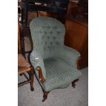 A Victorian stained mahogany deep buttoned spoon back easy chair, having scroll out arms and