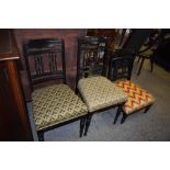 A pair of Victorian ebonised wood bedroom chairs with incised rails and spindled support, sold