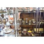 Two shelves of silver plated wares to include tea sets, condiment sets, trophy ball fish servers.