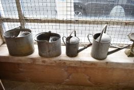 Two galvanized watering cans and two galvanized mop buckets.